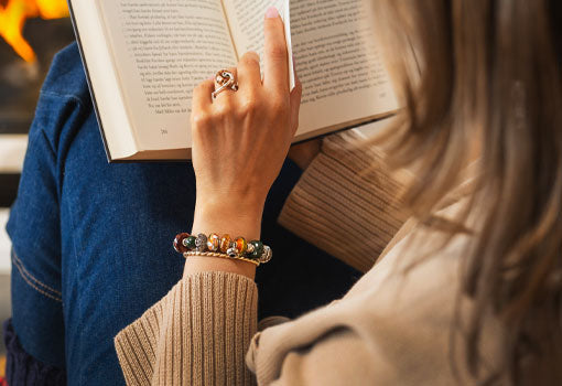 Person having a Hygge moment with a good book in front of the fireplace while wearing Trollbeads Hygge collection